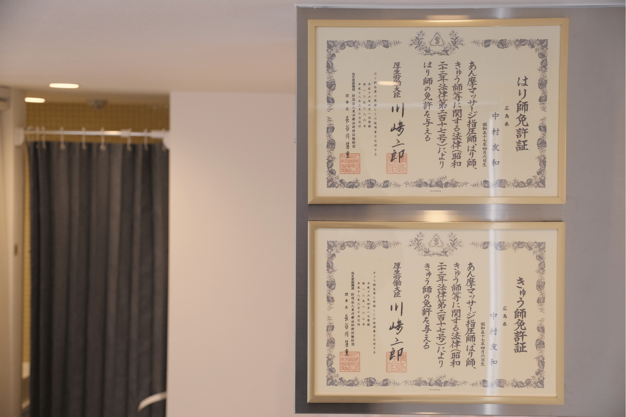 Two framed Japanese documents with calligraphy and red seals on beige background