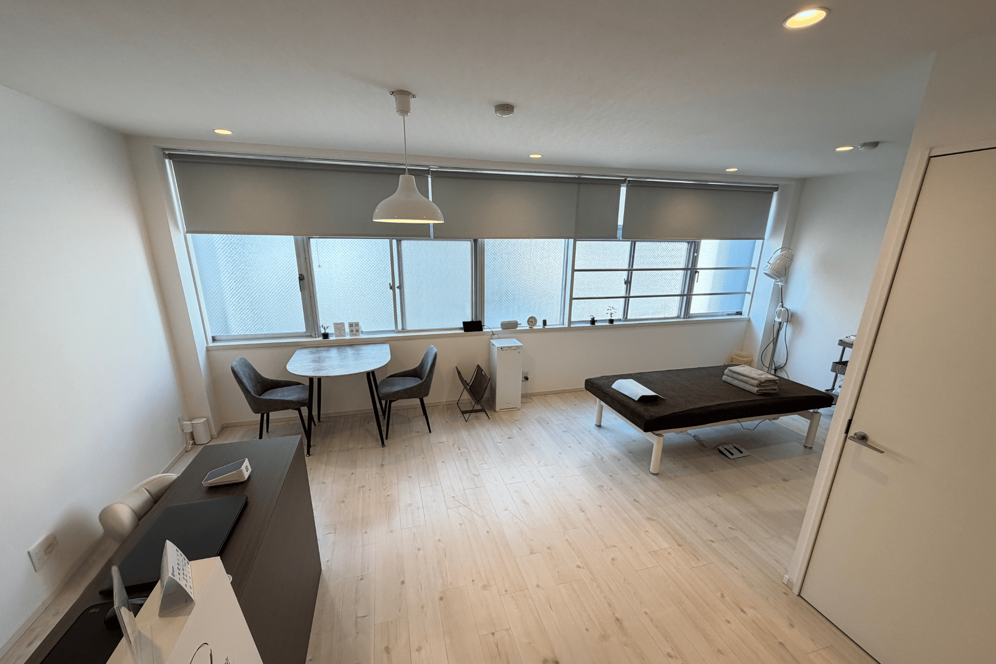 Modern apartment interior with dining table, bed, and floor-to-ceiling windows overlooking city