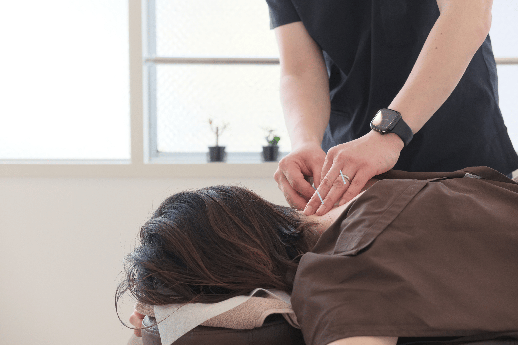 Massage therapist performing a neck massage on a client lying face down indoors