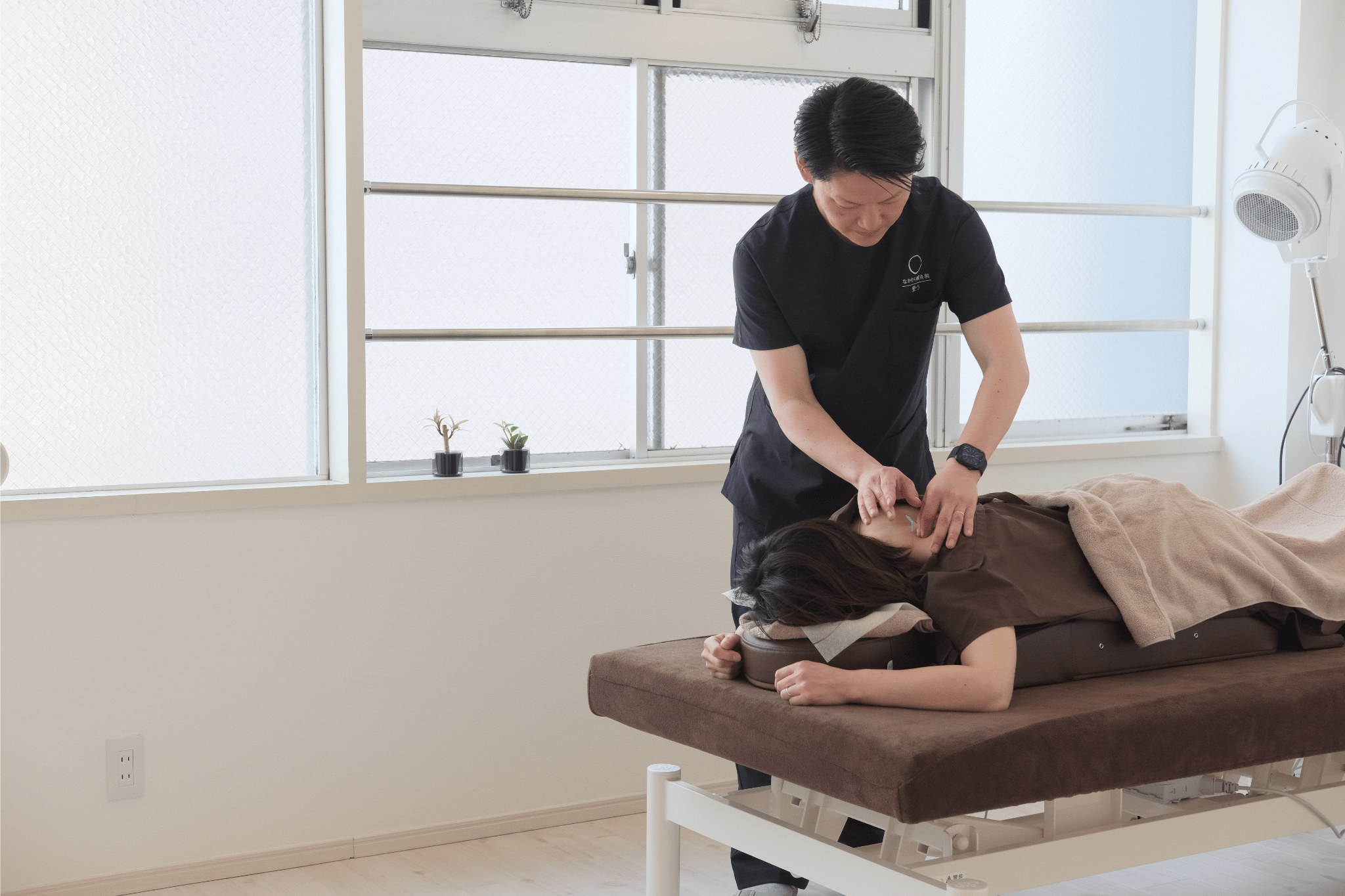 A massage therapist performs a back massage on a client lying face down on a treatment table